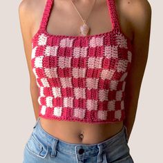 a woman wearing a pink and white crocheted crop top with her hands in her pockets