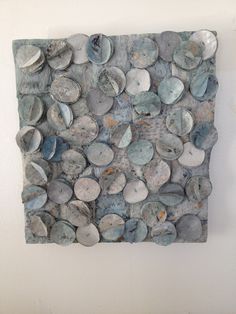 a piece of art made out of rocks on a wall with white walls behind it