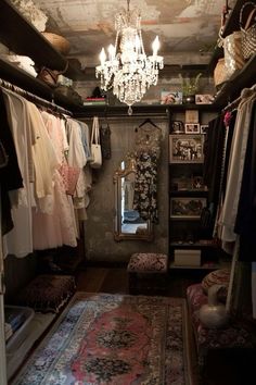 the closet is filled with clothes and chandelier hanging from it's ceiling