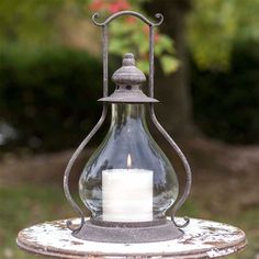 a lit candle is sitting on top of an old metal table outside in the sun