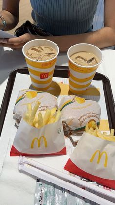 two mcdonald's cups and some french fries on a tray