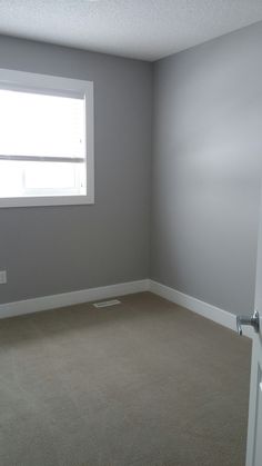 an empty room with a window and no curtains on the windowsill, in front of a white door