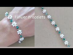 the bracelet is decorated with white flowers and green beads on it's side, while the