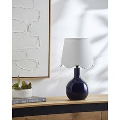 a blue vase sitting on top of a wooden table next to a white lamp shade