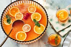 an orange drink in a bowl with lemons and mint garnish