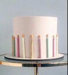 a white cake with pink frosting and candles