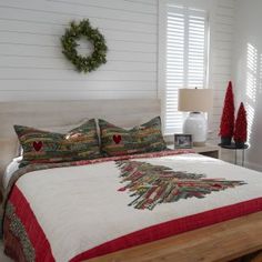 a bedroom with white walls and wooden floors, decorated in christmas decorations on the bed