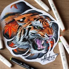 a tiger sticker sitting on top of a wooden table next to markers and pens