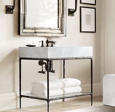 a bathroom with a sink, mirror and pictures on the wall above it is shown