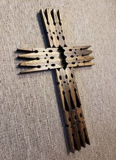 a wooden cross with holes in the middle on a gray cloth covered floor, close up