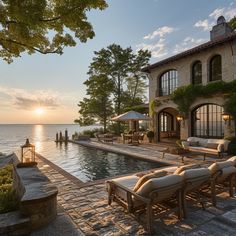 an outdoor swimming pool with chaise lounges next to it and the ocean in the background