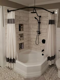 a bath tub sitting next to a white toilet in a bathroom under a shower curtain