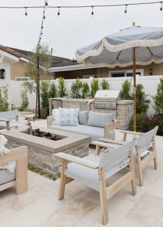 an outdoor living area with couches, chairs and an umbrella over the fire pit