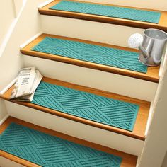 blue rugs on the steps leading up to a bucket and watering can with a newspaper