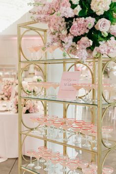 a display case filled with wine glasses and pink flowers