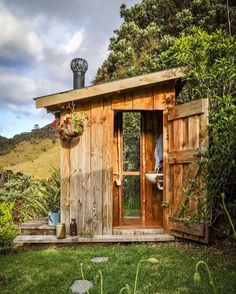 a small wooden outhouse sitting on top of a lush green field