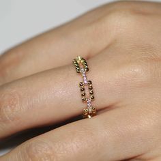 a woman's hand with a gold and diamond beaded ring on her finger