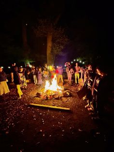 a group of people standing around a campfire at night