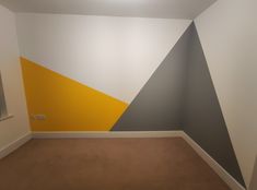 an empty room with yellow, grey and white paint on the wall in it's corner