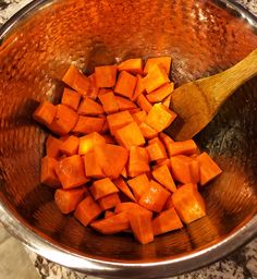 chopped up carrots in a metal bowl with a wooden spoon on the counter top