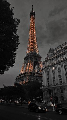 the eiffel tower lit up at night with cars parked in front of it