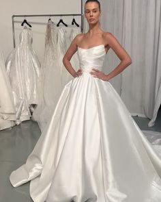 a woman in a white wedding dress standing next to a rack with dresses on it