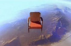 an orange chair floating in the air above earth