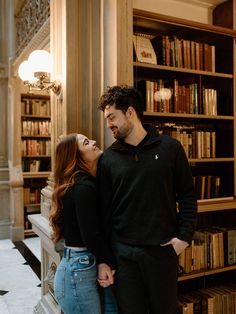 a man and woman standing next to each other in front of bookshelves