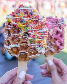 two people holding up ice cream cones with toppings