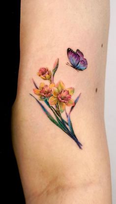 a tattoo with flowers and a butterfly on the side of her stomach, which is painted in watercolors