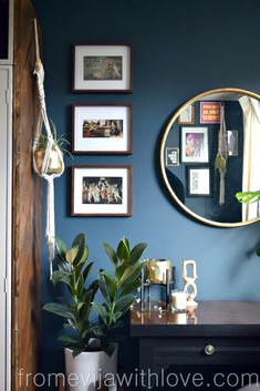 a room with blue walls and pictures on the wall, including a round mirror above a dresser