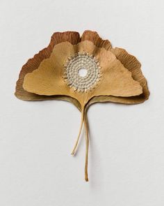 a large leaf shaped object on a white surface with a beaded center in the middle