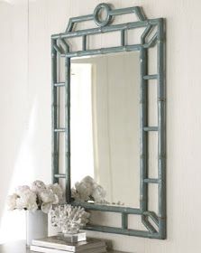 a mirror sitting on top of a shelf next to a vase with flowers in it