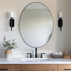 a bathroom sink with a round mirror above it