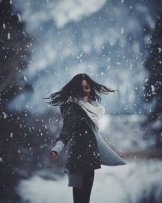 a woman walking in the snow with her hair blowing