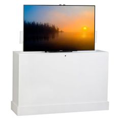 a tv sitting on top of a white stand with the sun setting in the background