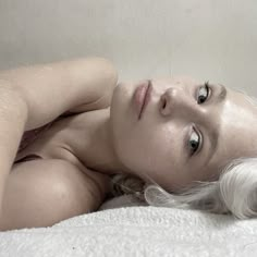 a woman laying on top of a bed next to a white wall