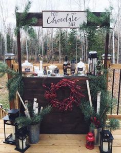 a hot chocolate bar decorated with greenery and christmas wreaths on a wooden deck