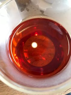 an orange liquid in a white bowl on top of a wooden table