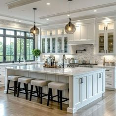 a large kitchen with white cabinets and marble counter tops, an island with four stools