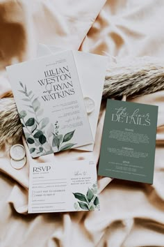 the wedding stationery is laid out on top of the bed with white linens and greenery