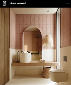 a bathroom with pink tiled walls and flooring, along with a large mirror on the wall