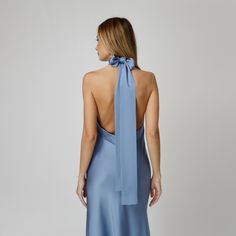 A captivating blend of elegance and allure, our Skye Open Back Halter Dress exudes undeniable charm. Tailored with a flattering bias cut from blue double silk satin, it drapes gracefully over the silhouette. The halter neckline delicately frames the shoulders, while the revealing back adds a note of sensuality. For a playful and feminine look, you can transform the silk tie neck into a chic bow, or you can let it drape loosely, adding a touch of laid-back sophistication to your ensemble.  Wear it with flats for an effortlessly refined look or dress it up with a precious pair of heels. Each Il Volo item is handmade by skilful artisans in our Bucharest atelier and it is created in limited series. 100% Italian Double Silk Satin.  Gentle dry clean. Do not wash. Do not use chlorine based bleach Elegant Tie Back Satin Dress For Evening, Wedding Silk Satin Dress With Tie Back, Wedding Silk Satin Tie-back Dress, Elegant Blue Tie Back Slip Dress, Satin Tie Back Dresses For Wedding Guests, Elegant Satin Tie-back Dress For Gala, Elegant Blue Slip Dress With Tie Back, Elegant Satin Dress With Tie Back For Gala, Elegant Silk Satin Dress With Tie Back