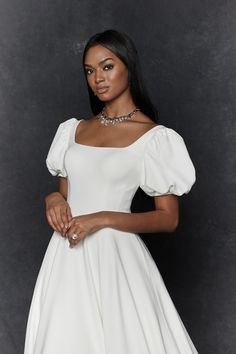 a woman in a white dress posing for the camera with her hand on her hip