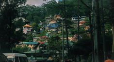 cars are parked on the street in front of some houses and trees with mountains in the background