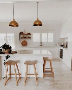 two stools are in the middle of a kitchen with white countertops and cabinets