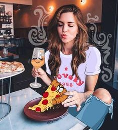 a woman sitting at a table with a plate of pizza and a glass of wine