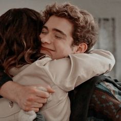 a man and woman hug each other while sitting on a couch