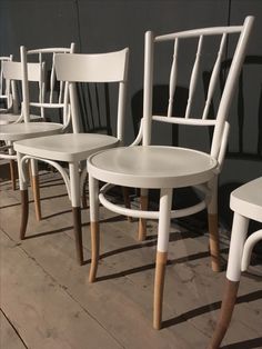 four white chairs sitting side by side in a row on the floor next to each other