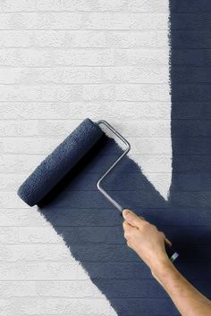 a person holding a paint roller in their hand and painting the wall with blue color